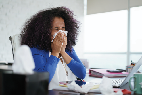 Woman working and sneezing